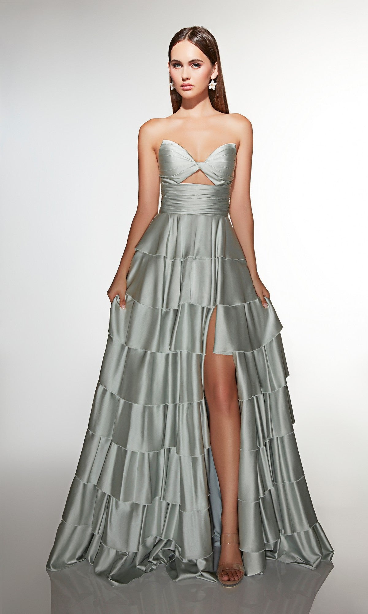 A woman wears the Alyce 61987 long prom dress—strapless, silver satin with ruffles and a front slit—standing against a plain light background.
